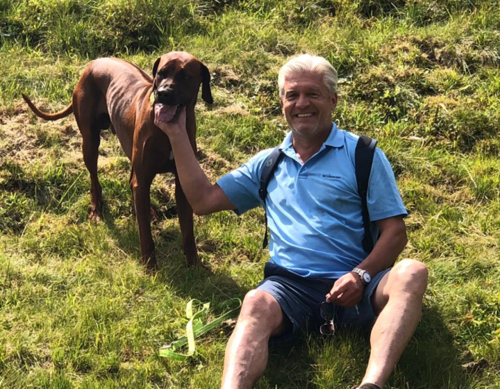 Gastgeber Karl mit seinem Hund auf einer Bergwiese bei Oberstdorf – Urlaub mit Hund in der Villa Alpjuwel